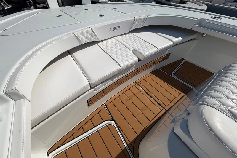 Slide: The Image of 2023 Costa Custom Boats 264 HC interior with white seating and teak flooring. - 12