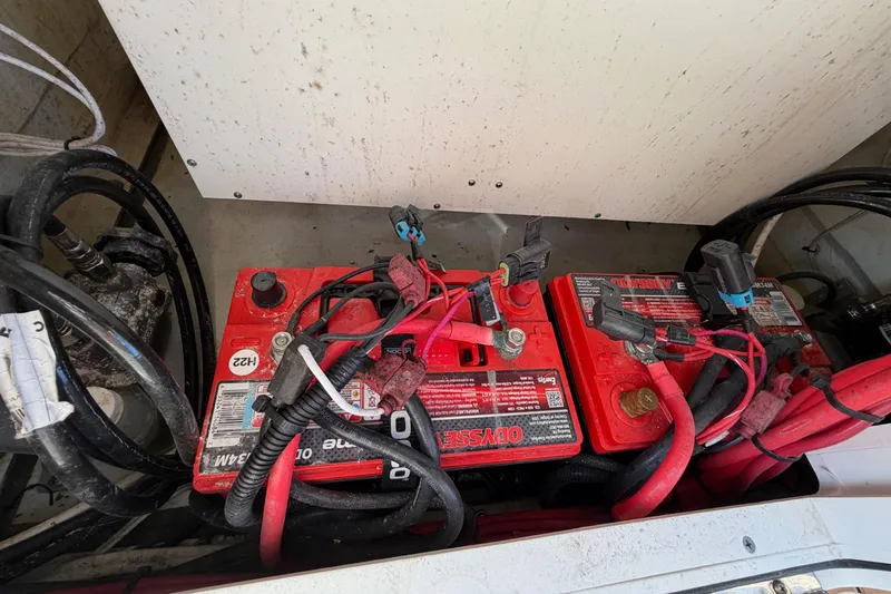 Slide: The Image of Batteries in a 2023 Costa Custom Boats 264 HC, featuring red cables and connectors. - 60