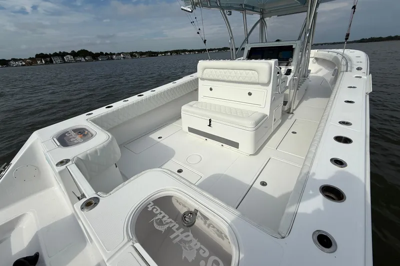 Slide: The Image of 2018 SeaHunter 35 Tournament boat interior with seating and fishing rod holders on calm water. - 13