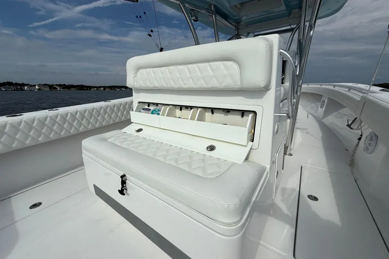 Slide: The Image of 2018 SeaHunter 35 Tournament boat interior with white seating and storage, on calm water. - 27