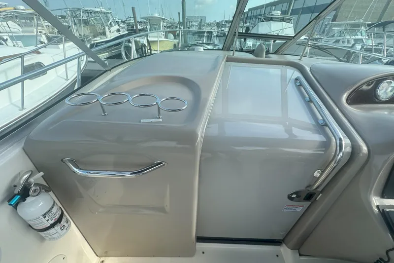 Slide: The Image of 2006 Sea Ray 290 Amberjack cockpit with cup holders and fire extinguisher, docked at marina. - 23