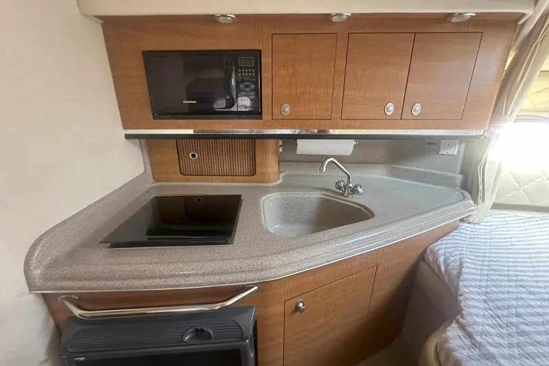 Slide: The Image of 2006 Sea Ray 290 Amberjack galley with microwave, sink, and stove. - 31