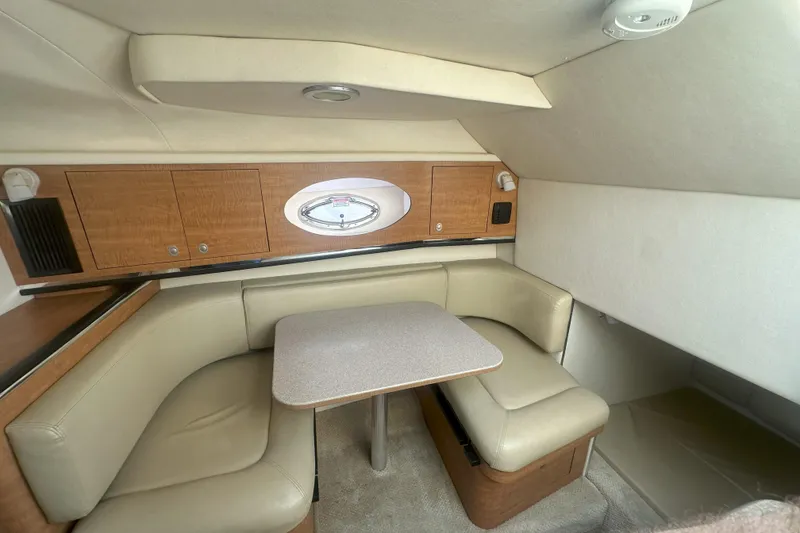 Slide: The Image of 2006 Sea Ray 290 Amberjack cabin interior with beige seating and wooden cabinetry. - 27