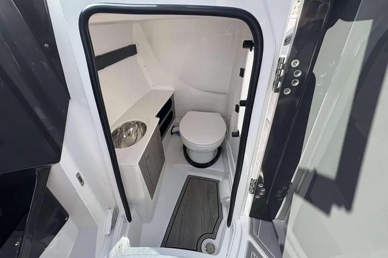 Slide: The Image of Interior of 2026 Monterey 275SS Super Sport boat, featuring a compact bathroom with toilet and sink. - 19