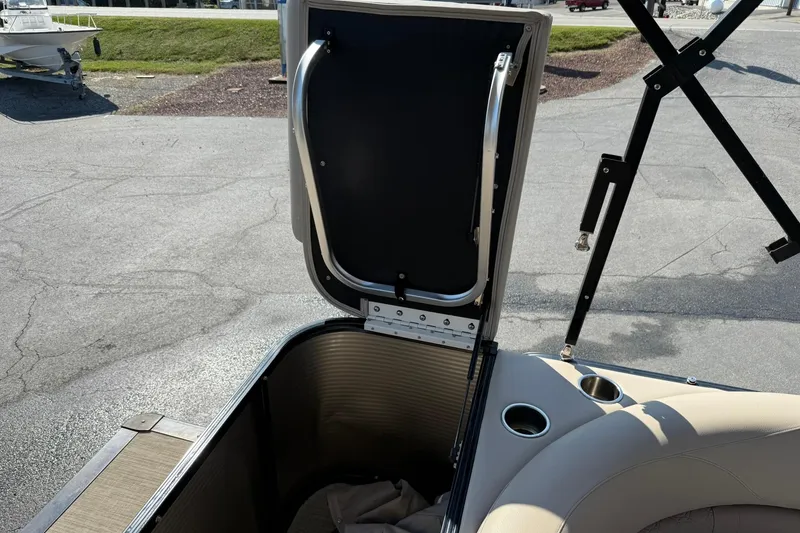 Slide: The Image of 2018 Avalon GS Cruise II boat storage compartment with open hatch and cup holders. - 16