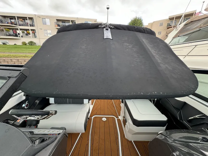 Slide: The Image of 2022 Monterey 258 Super Sport boat interior with black canopy and wooden deck. - 49