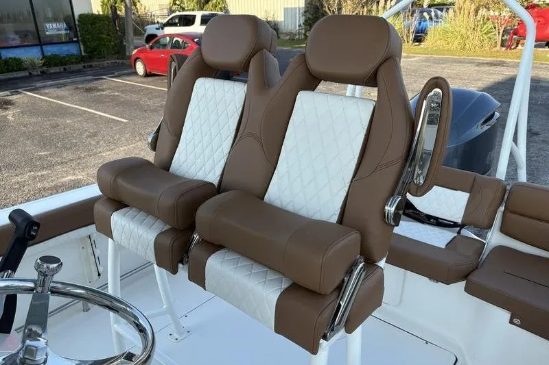 Slide: The Image of 2026 Pioneer Islander 222 boat seats with brown and white upholstery in a parking lot. - 15