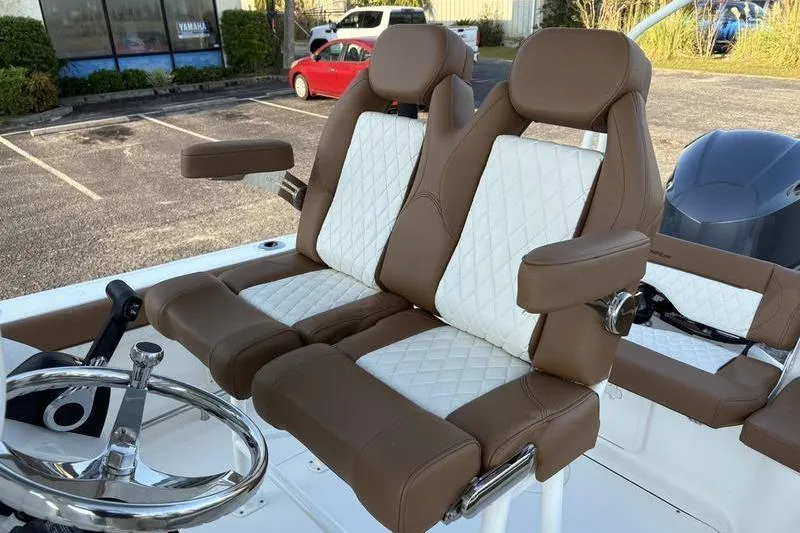 Slide: The Image of 2026 Pioneer Islander 222 boat seats with brown and white upholstery in a parking lot. - 16