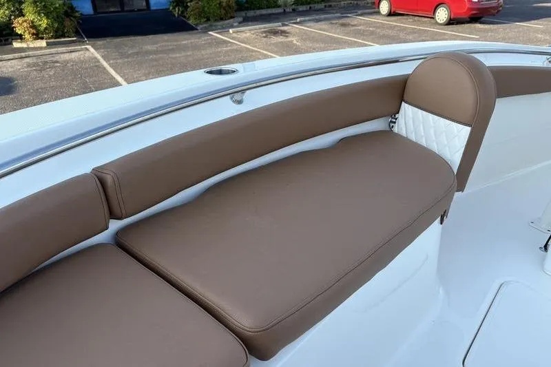 Slide: The Image of 2026 Pioneer Islander 222 boat with brown cushioned seating in a parking lot. - 29