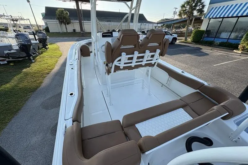 Slide: The Image of 2026 Pioneer Islander 222 boat interior with brown seating and white deck, parked outdoors. - 33