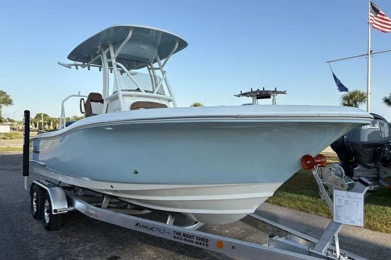 Slide: The Image of 2026 Pioneer Islander 222 boat on trailer, displayed outdoors with flags in the background. - 6