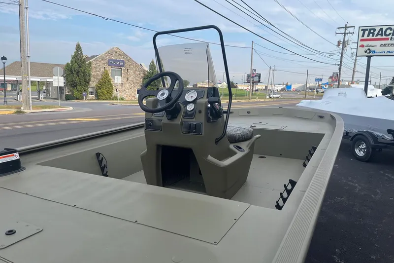 Slide: The Image of 2026 Tracker Grizzly 1860 CC boat with center console, parked outdoors near a road. - 5