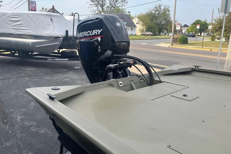 Slide: The Image of 2026 Tracker Grizzly 1860 CC boat with Mercury outboard motor in a parking lot. - 6