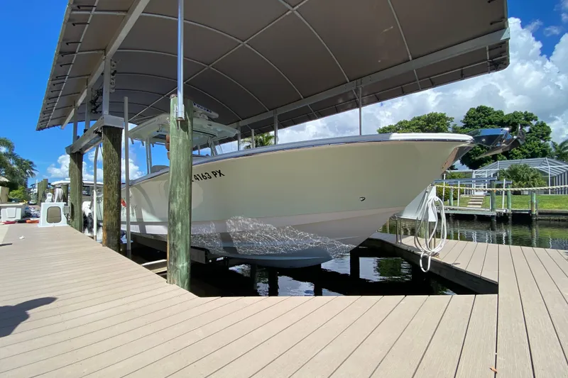 The Image of 2015 Edgewater 320CC boat docked under a canopy on a sunny day. - 0