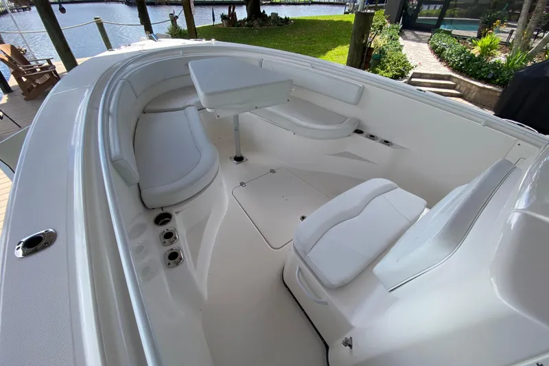 Slide: The Image of 2015 Edgewater 320CC boat interior with white seating and table, docked by a waterfront. - 14