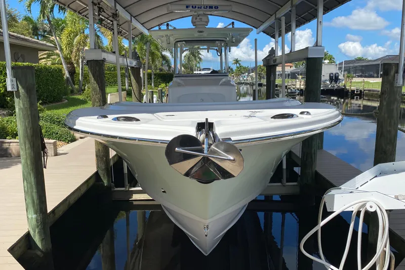 Slide: The Image of 2015 Edgewater 320CC boat docked under a canopy, surrounded by lush greenery. - 2