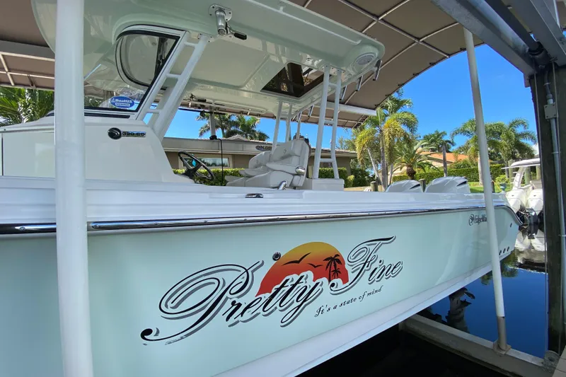 Slide: The Image of 2015 Edgewater 320CC boat docked, featuring "Pretty Fine" graphic and tropical design. - 3