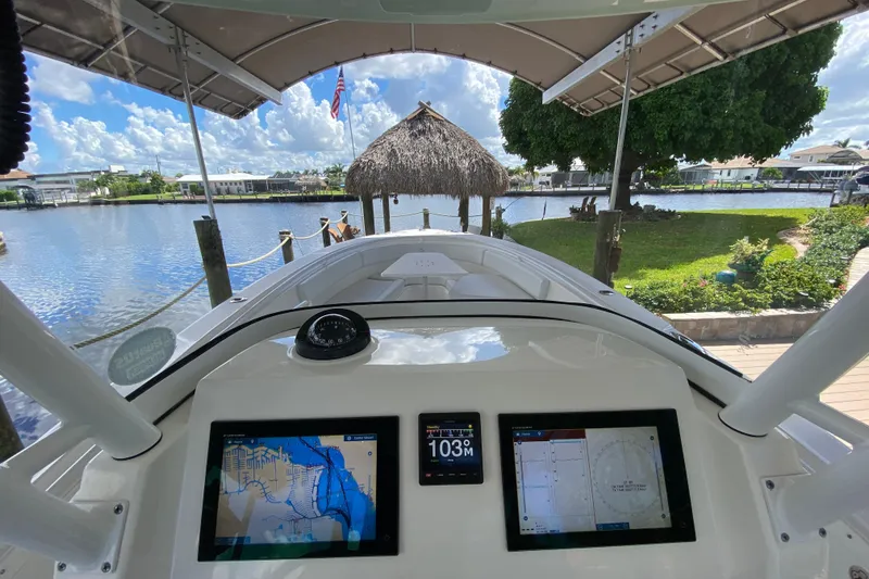 Slide: The Image of Edgewater 320CC boat dashboard with navigation screens, docked by a scenic waterfront. - 33