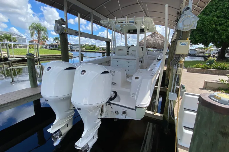 Slide: The Image of 2015 Edgewater 320CC boat with dual engines docked under a canopy. - 4