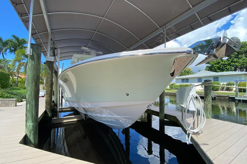 Slide: The Image of 2015 Edgewater 320CC boat docked under canopy, surrounded by tropical scenery. - 6