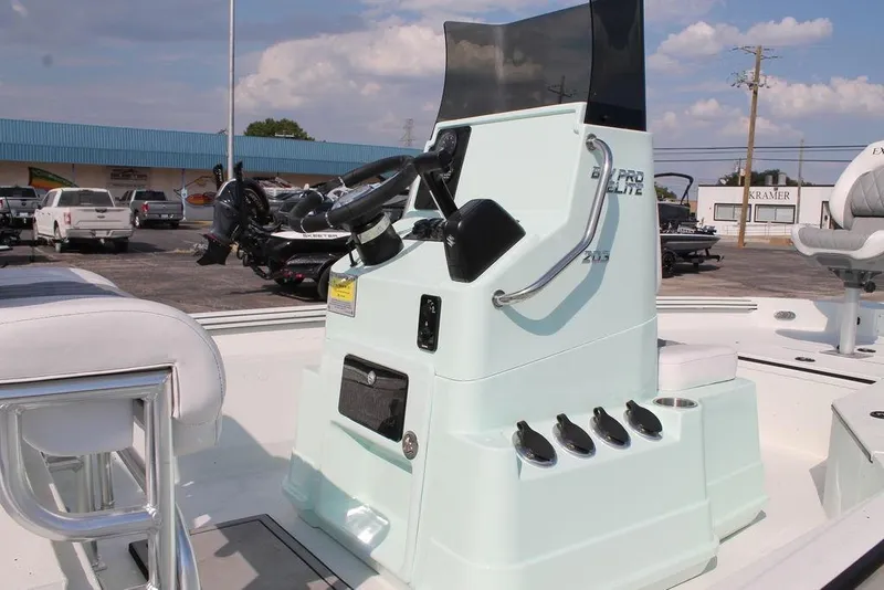 Slide: The Image of 2026 Excel Bay Pro Elite 203 boat console with steering wheel and controls, parked outdoors. - 11