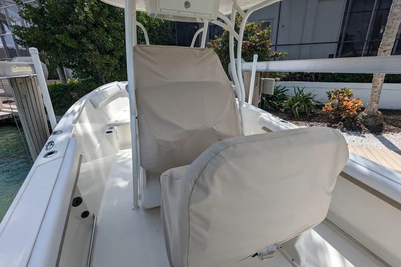 Slide: The Image of 2016 Sailfish 240 CC boat interior with covered seating, docked near lush greenery. - 4