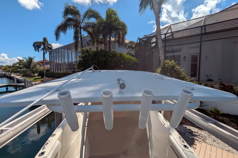 Slide: The Image of 2016 Sailfish 240 CC boat with rod holders, docked near palm trees and waterfront homes. - 6