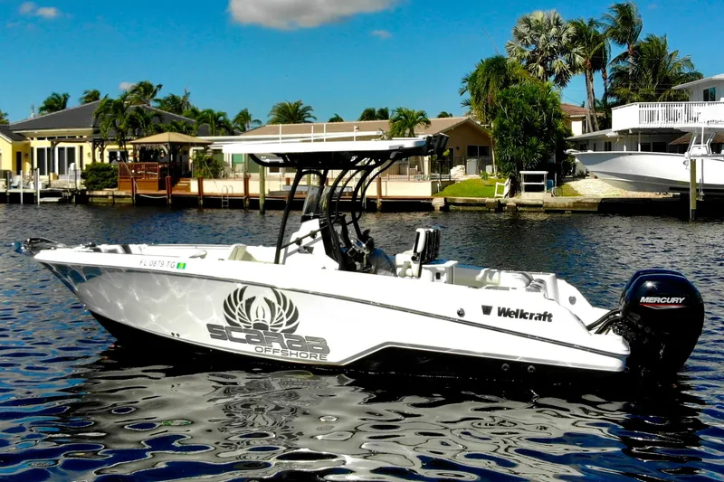 Slide: The Image of 2022 Wellcraft 242 Fisherman boat on water, featuring Mercury engine, with waterfront homes in background. - 2