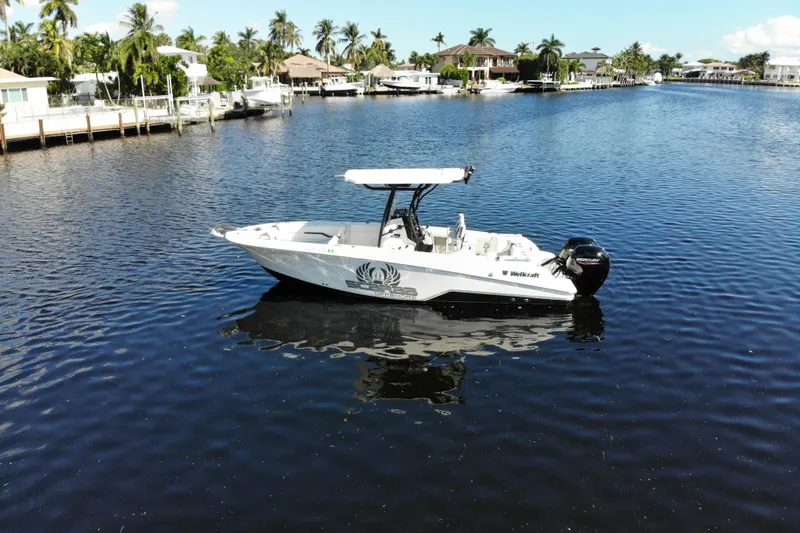 Slide: The Image of 2022 Wellcraft 242 Fisherman boat on a calm waterway, surrounded by waterfront homes and palm trees. - 3