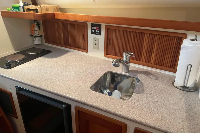Slide: The Image of Compact kitchen area in a 1998 Little Harbor WhisperJet 36 boat, featuring a sink and stove. - 16