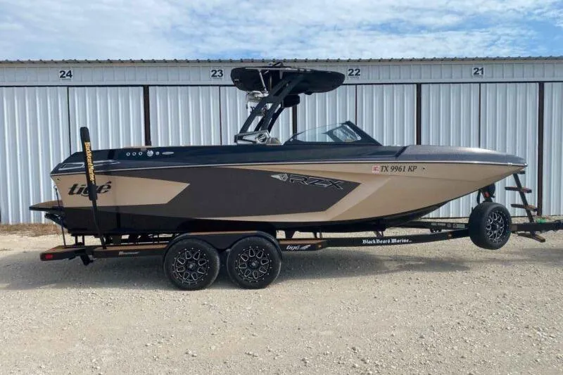 The Image of 2021 Tigé 23RZX boat on trailer, parked in front of storage units. - 1