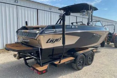 Slide: The Image of 2021 Tigé 23RZX boat on trailer, parked near storage units. - 6