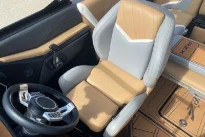 Slide: The Image of 2021 Tigé 23RZX boat interior with tan and gray seating, modern steering wheel. - 9