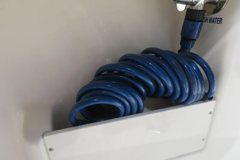 Slide: The Image of Coiled blue hose on 2021 Key West 239 FS boat, fresh water connection visible. - 43