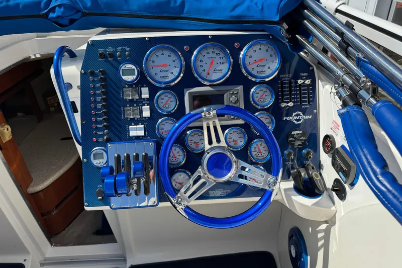 Slide: The Image of 2008 Fountain 35 Lightning boat dashboard with blue accents and multiple gauges. - 13