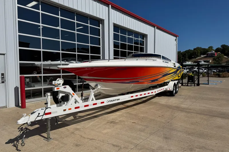 Slide: The Image of 2008 Fountain 35 Lightning boat on trailer outside a garage, vibrant orange and yellow design. - 2