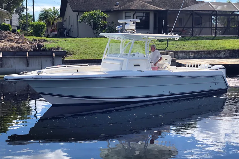 The Image of 2016 Tarpon 326 boat on calm water near a residential area. - 0
