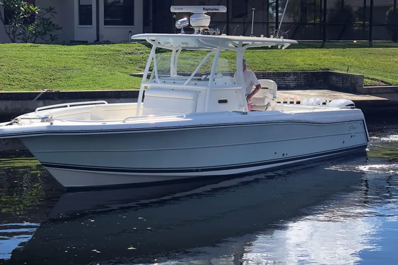 Slide: The Image of 2016 Tarpon 326 boat cruising on a calm waterway near a grassy shoreline. - 1