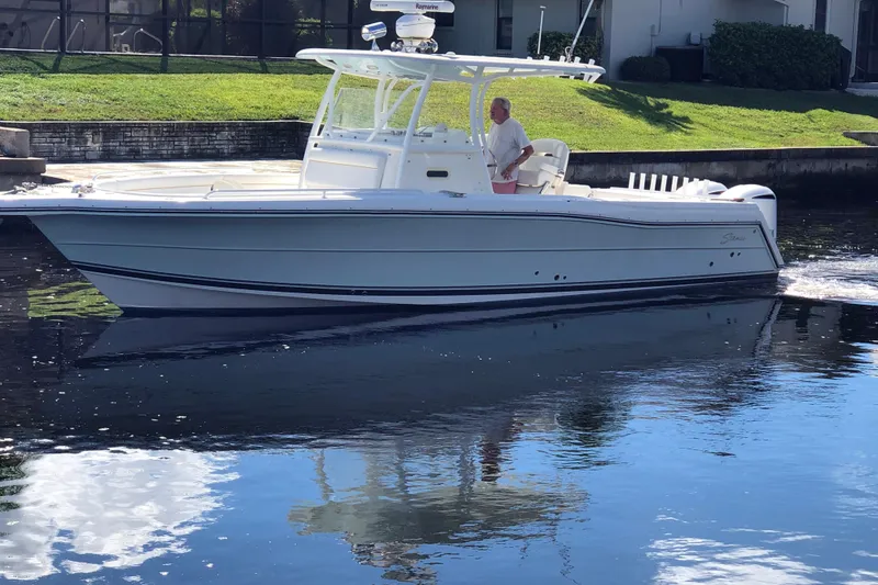 Slide: The Image of A 2016 Tarpon 326 boat cruising on calm water near a grassy shoreline. - 2