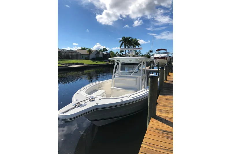 Slide: The Image of 2016 Tarpon 326 boat docked on a sunny day, surrounded by palm trees. - 4