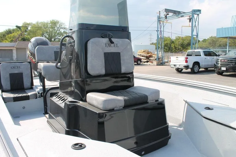 Slide: The Image of 2026 Excel Bay Pro Elite 203 boat interior with seating and console, parked outdoors. - 8
