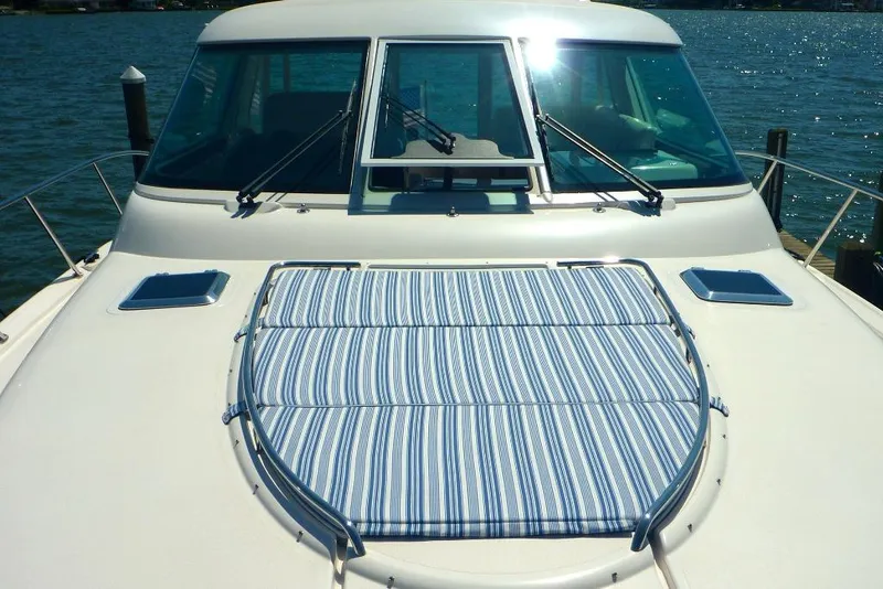 Slide: The Image of 2006 Tiara 44' Sovran yacht with striped sun pad on deck, docked by the water. - 5