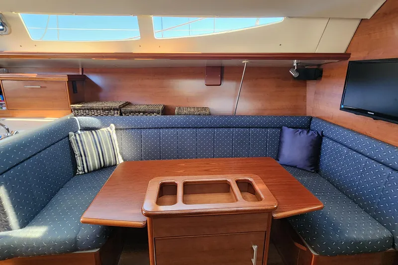 Slide: The Image of 2012 Hunter e 33 yacht interior with blue cushioned seating and wooden table. - 15
