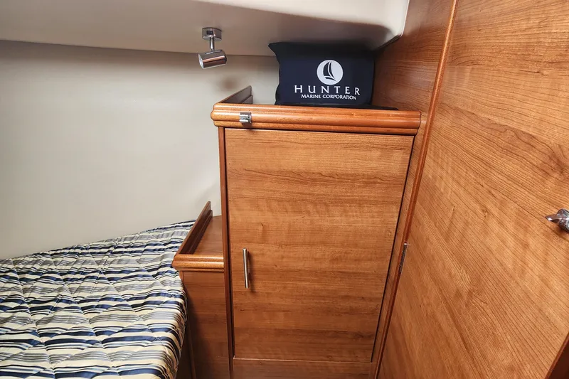 Slide: The Image of Interior cabin of 2012 Hunter e 33 sailboat with wooden cabinetry and striped bedding. - 17