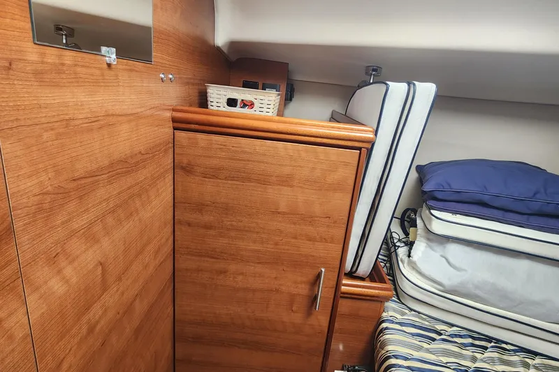 Slide: The Image of Interior of 2012 Hunter e 33 sailboat with wooden cabinetry and stacked cushions. - 18