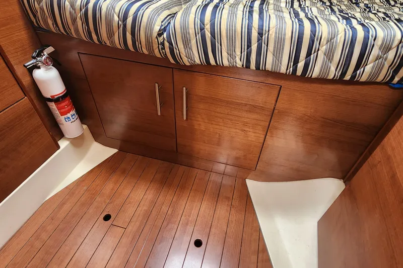 Slide: The Image of 2012 Hunter e 33 interior with wood cabinetry, striped bedding, and fire extinguisher. - 20