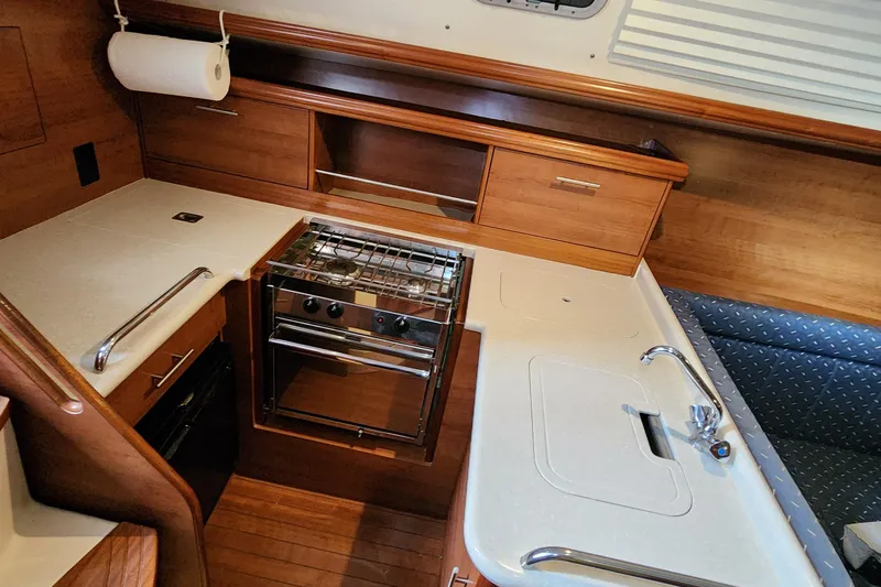 Slide: The Image of Interior of 2012 Hunter e 33 sailboat kitchen with stove, sink, and wooden cabinetry. - 8