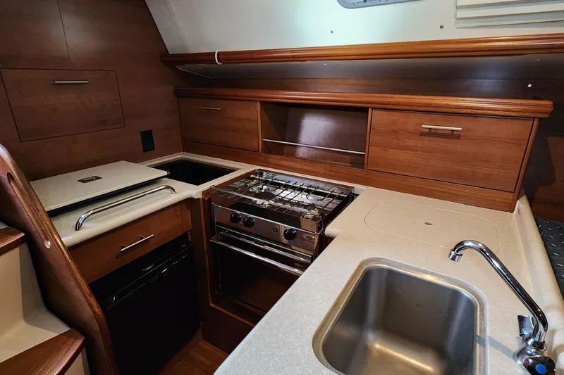 Slide: The Image of 2012 Hunter e 33 yacht kitchen with stove, sink, and wooden cabinetry. - 9