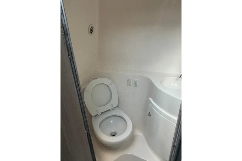 Slide: The Image of Compact bathroom in 2021 Regal 26 Express boat, featuring a toilet and sink. - 9