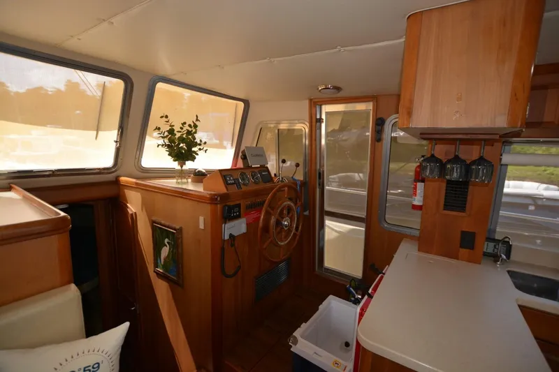 Slide: The Image of 2004 Mainship 400 Trawler interior with helm, wooden cabinetry, and large windows. - 11